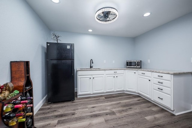 kitchen featuring white cabinets, light hardwood / wood-style flooring, sink, and black fridge