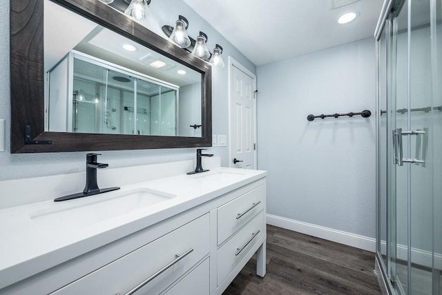 bathroom with vanity, a shower with shower door, and wood-type flooring