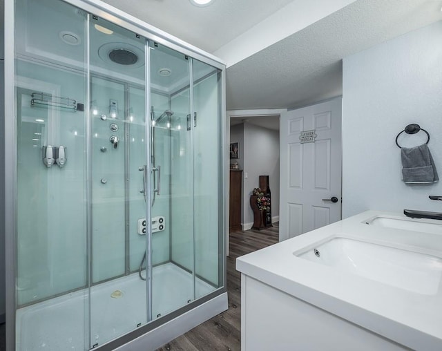 bathroom featuring a textured ceiling, vanity, wood-type flooring, and a shower with shower door