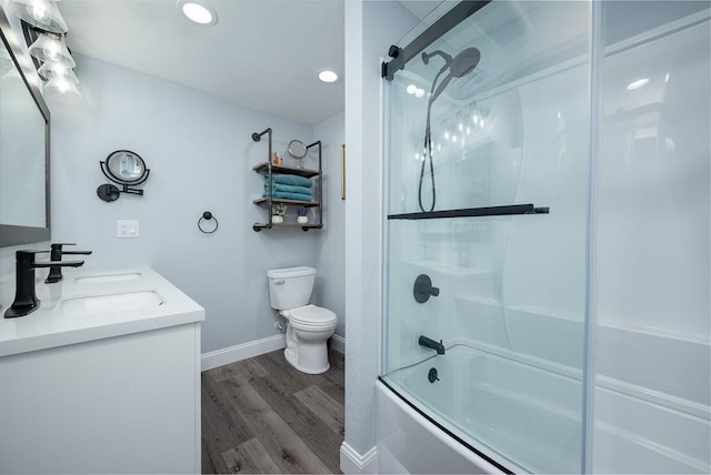 full bathroom featuring toilet, vanity, hardwood / wood-style floors, and enclosed tub / shower combo