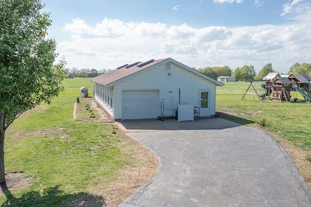 view of side of property with a playground, a lawn, and a garage