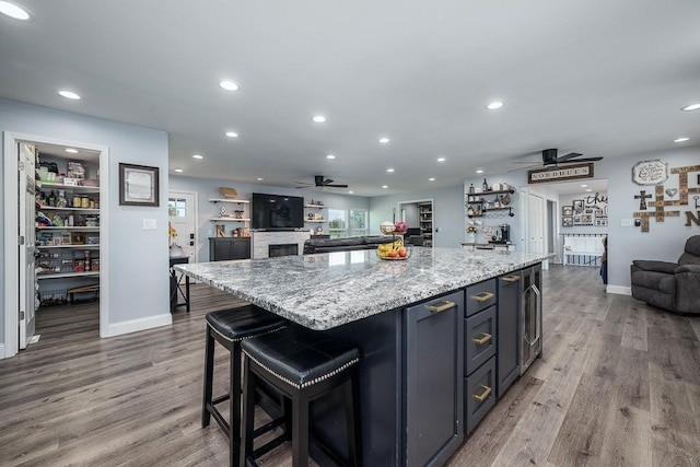 kitchen with light stone counters, ceiling fan, hardwood / wood-style floors, a kitchen island, and a healthy amount of sunlight