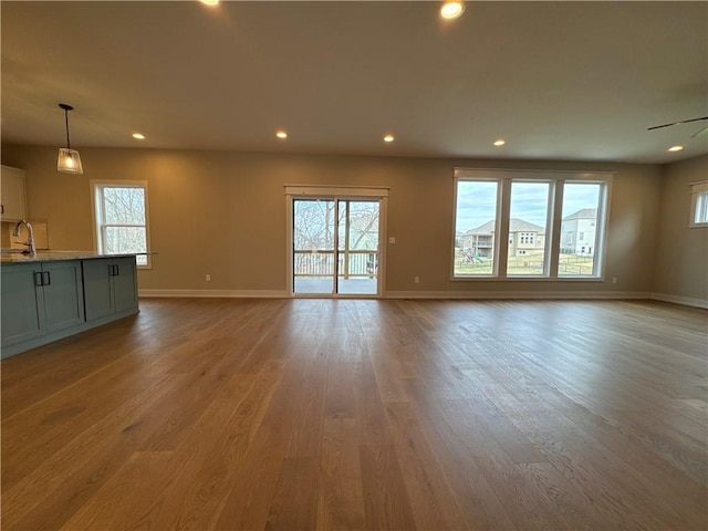 unfurnished living room featuring plenty of natural light, sink, and light hardwood / wood-style floors