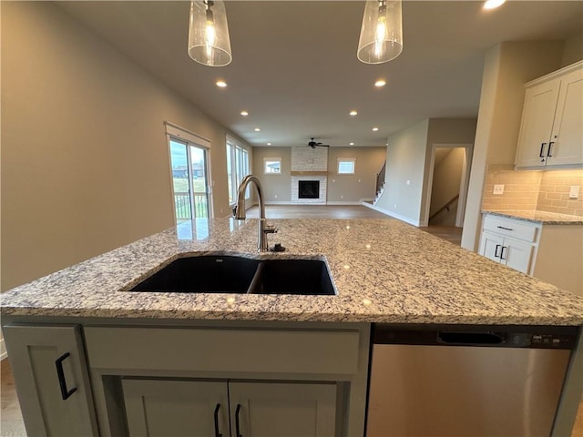 kitchen with a center island with sink, pendant lighting, sink, and stainless steel dishwasher