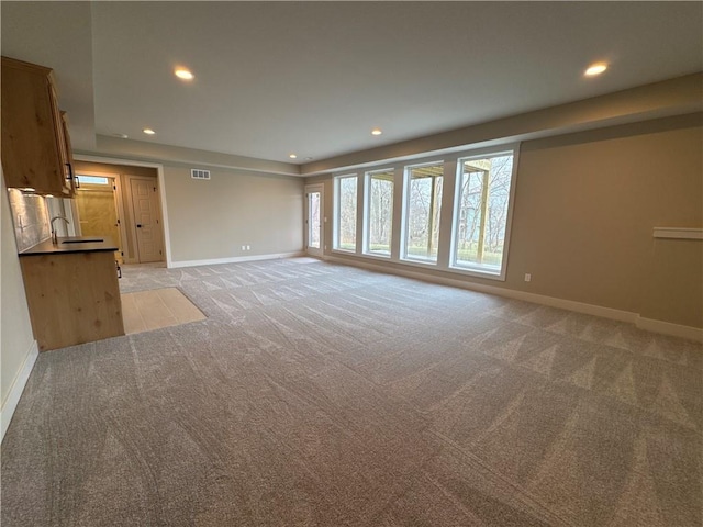 unfurnished living room featuring sink and light carpet