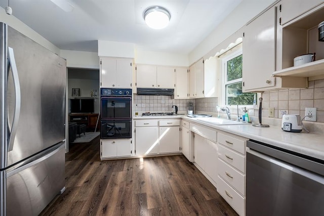 kitchen featuring appliances with stainless steel finishes, dark wood-type flooring, white cabinets, backsplash, and sink