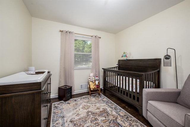 bedroom featuring a crib and dark wood-type flooring