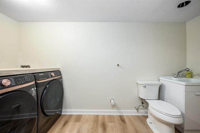 washroom featuring light wood-type flooring, separate washer and dryer, and sink