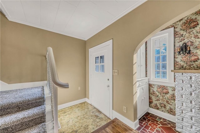 entrance foyer featuring crown molding, arched walkways, brick floor, wallpapered walls, and baseboards