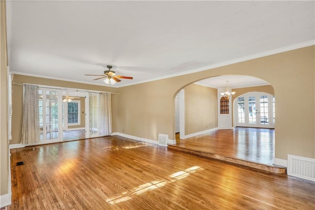 spare room with hardwood / wood-style flooring, ceiling fan with notable chandelier, ornamental molding, and french doors