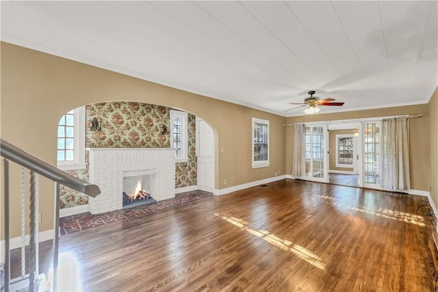 unfurnished living room with hardwood / wood-style flooring, a fireplace, ornamental molding, and a healthy amount of sunlight