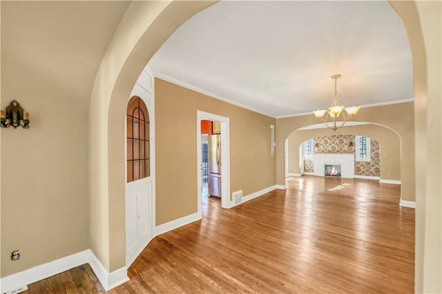 interior space with an inviting chandelier, crown molding, and hardwood / wood-style flooring