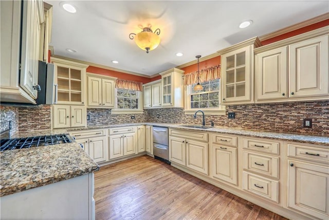 kitchen featuring hanging light fixtures, cream cabinets, sink, and light stone counters