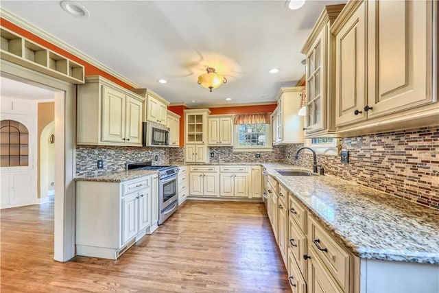 kitchen with appliances with stainless steel finishes, light stone countertops, sink, and backsplash