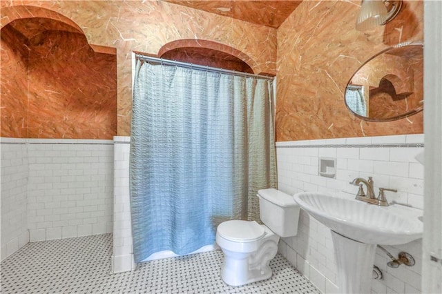 bathroom with toilet, tile walls, and a shower with curtain