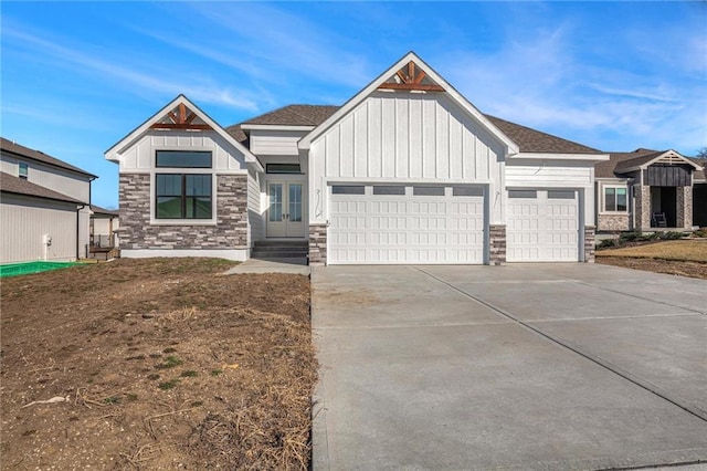 view of front of home with concrete driveway, an attached garage, board and batten siding, and stone siding