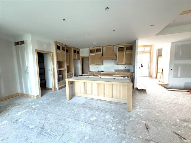 kitchen with premium range hood and a kitchen island with sink