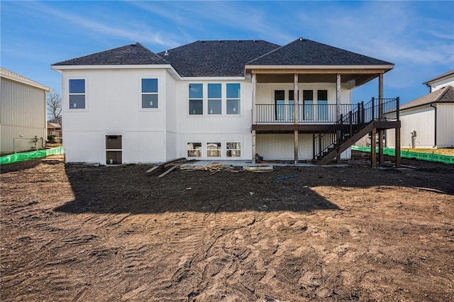 rear view of property with stairway and roof with shingles