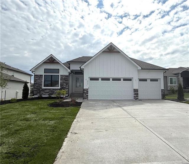 3215 SW Enoch St, Lees Summit, MO 64082 - view of front facade with stone siding, an attached garage, a front yard, board and batten siding, and concrete driveway
