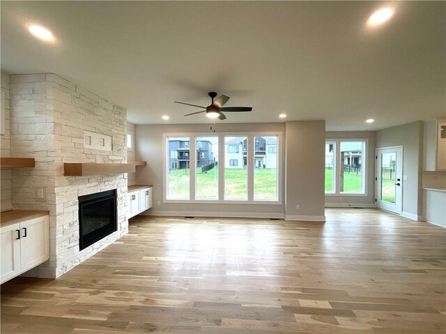 unfurnished living room featuring ceiling fan, light wood-type flooring, and a fireplace