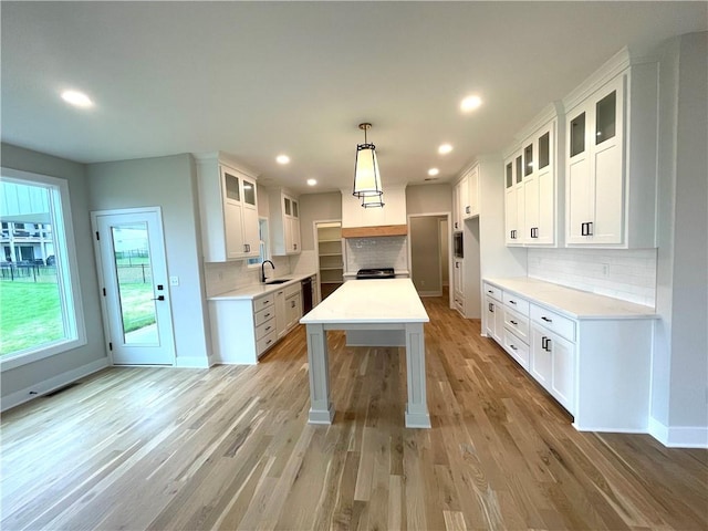 kitchen with light hardwood / wood-style flooring, pendant lighting, tasteful backsplash, sink, and white cabinets