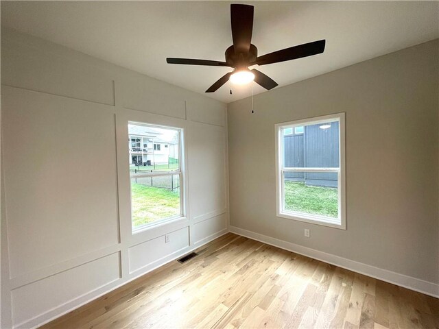 spare room featuring a healthy amount of sunlight, ceiling fan, and light hardwood / wood-style floors