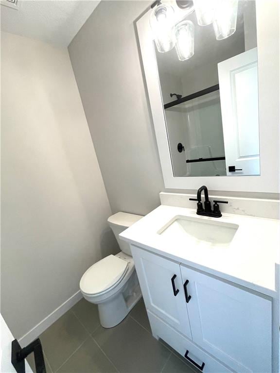 bathroom with tile patterned flooring, vanity, toilet, and a shower