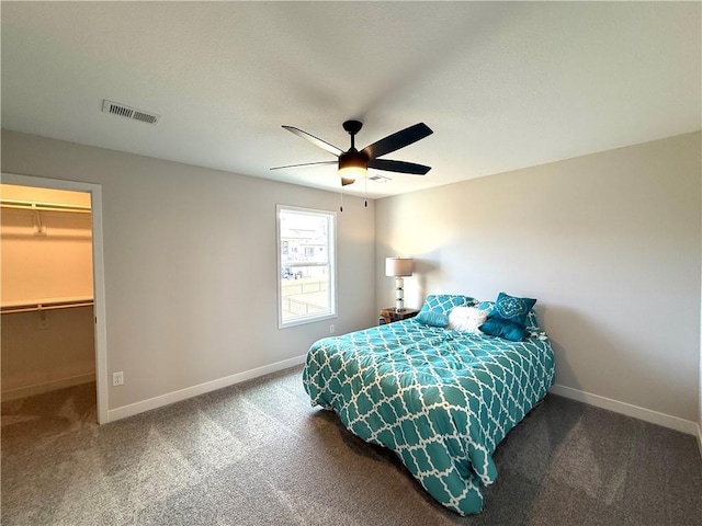 bedroom with visible vents, a walk in closet, ceiling fan, carpet, and baseboards