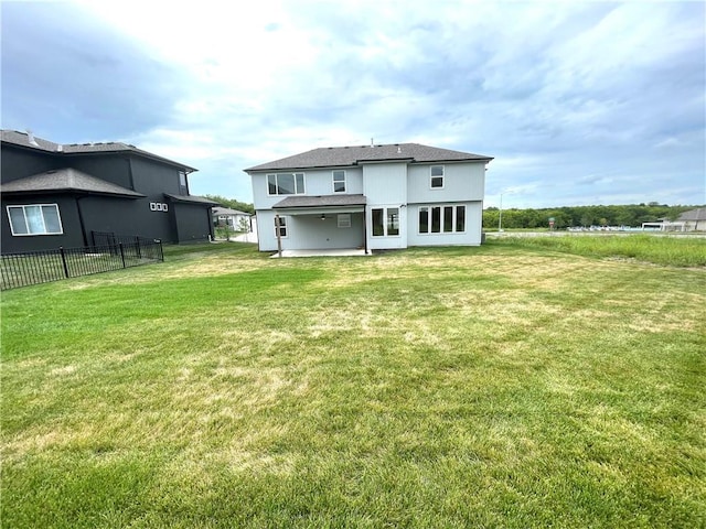 rear view of property with a patio, a lawn, and fence