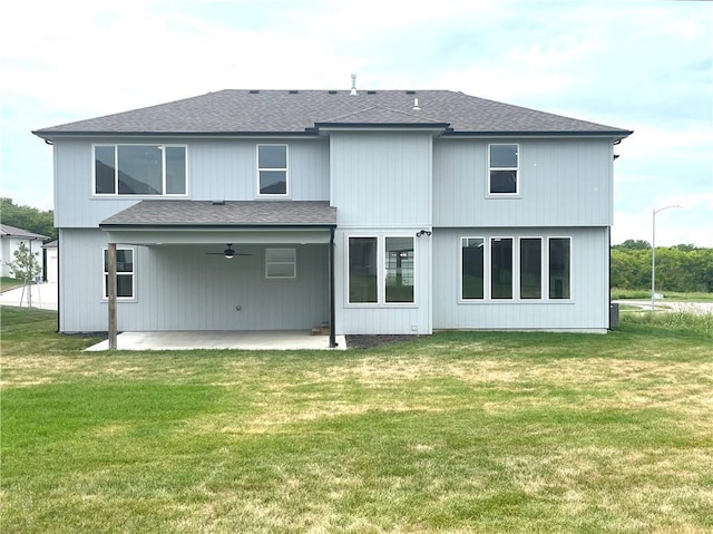 rear view of property featuring a patio, a lawn, a ceiling fan, and a shingled roof