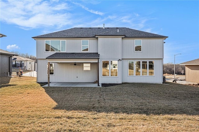 back of property with a yard, a patio, and roof with shingles