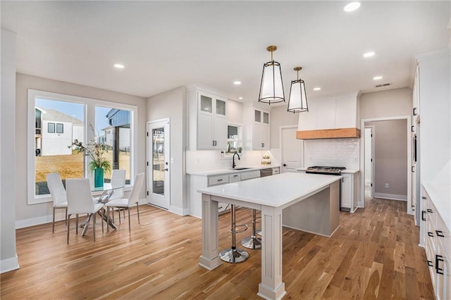 kitchen featuring a sink, tasteful backsplash, a center island, and light countertops