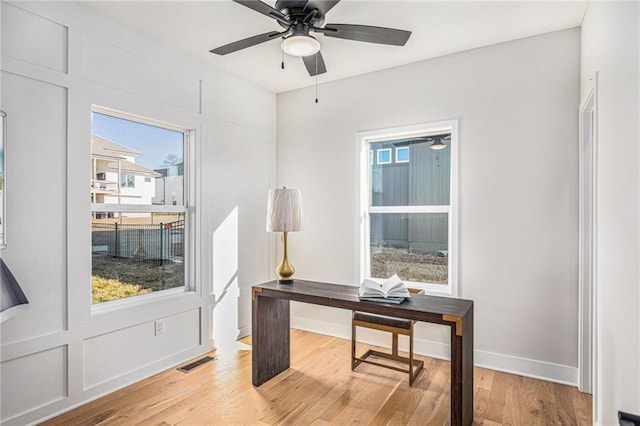 home office with visible vents, baseboards, ceiling fan, and light wood finished floors