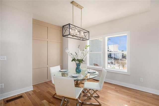 dining space featuring a notable chandelier, light wood-style floors, visible vents, and baseboards