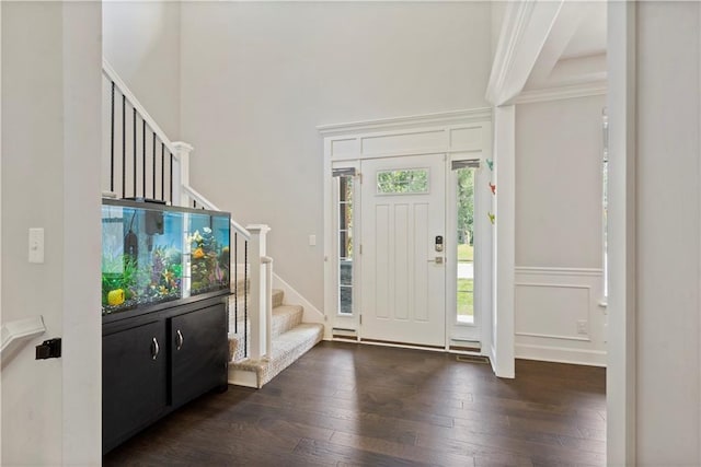 foyer with a decorative wall, stairway, dark wood-style flooring, and a towering ceiling