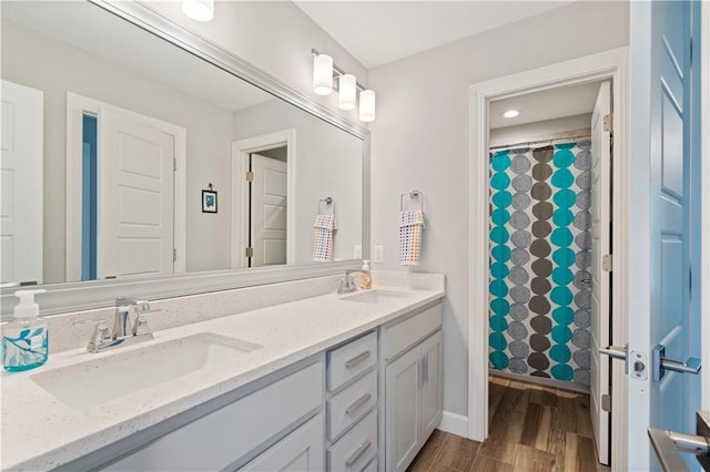 full bathroom featuring a sink, double vanity, curtained shower, and wood finished floors