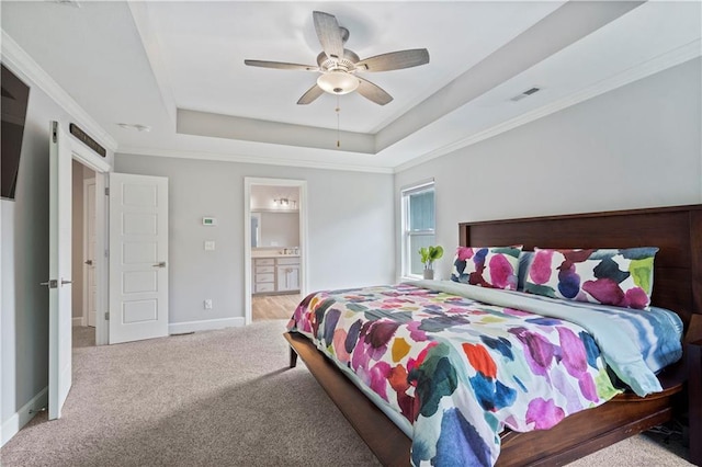 carpeted bedroom featuring baseboards, ornamental molding, ensuite bath, visible vents, and a raised ceiling