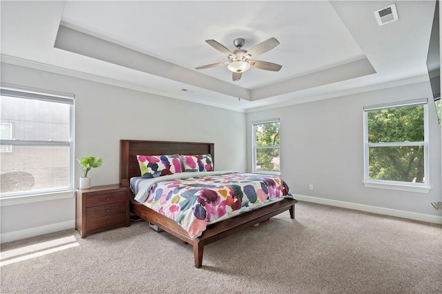 bedroom with visible vents, baseboards, a raised ceiling, a ceiling fan, and light colored carpet