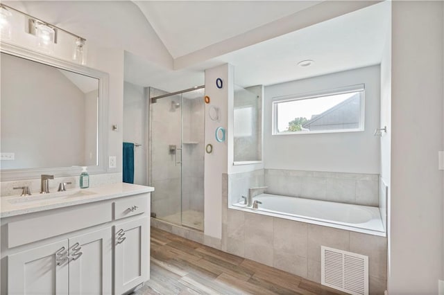 bathroom featuring vaulted ceiling, a shower stall, visible vents, a garden tub, and wood finished floors