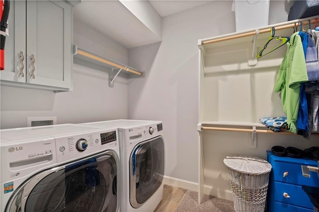 clothes washing area with independent washer and dryer, light wood-type flooring, and baseboards