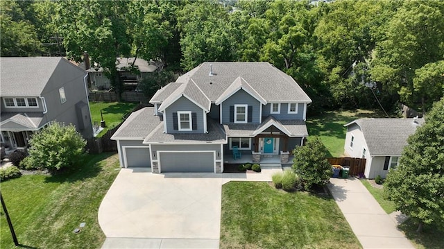 view of front facade with stone siding, a garage, fence, concrete driveway, and a front lawn