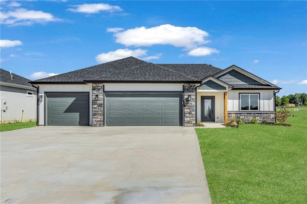 view of front of home featuring a front lawn, stone siding, board and batten siding, concrete driveway, and a garage