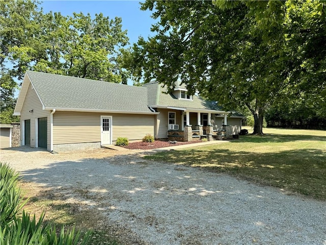 view of front facade featuring a front yard, a porch, cooling unit, an outdoor structure, and a garage