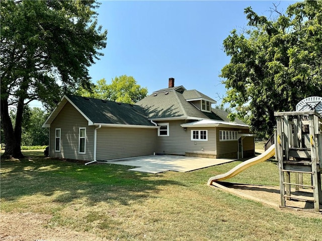 back of house featuring a playground, a lawn, and a patio