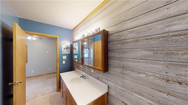 bathroom with vanity, ceiling fan, and wood walls