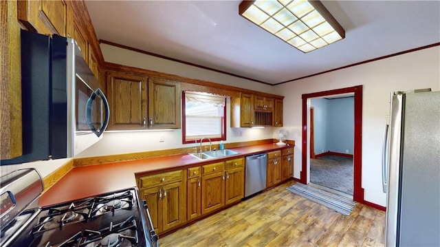 kitchen with crown molding, appliances with stainless steel finishes, sink, and light hardwood / wood-style floors