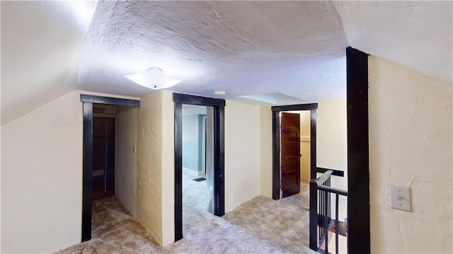 hallway featuring lofted ceiling and light carpet