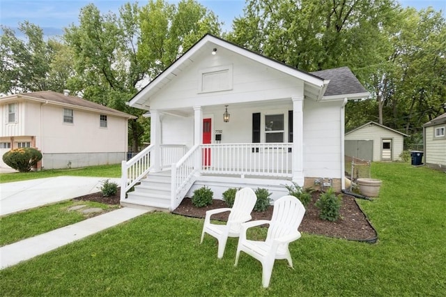 bungalow-style home with a porch, a front lawn, and a storage shed