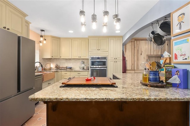 kitchen featuring decorative light fixtures, stainless steel appliances, and cream cabinetry