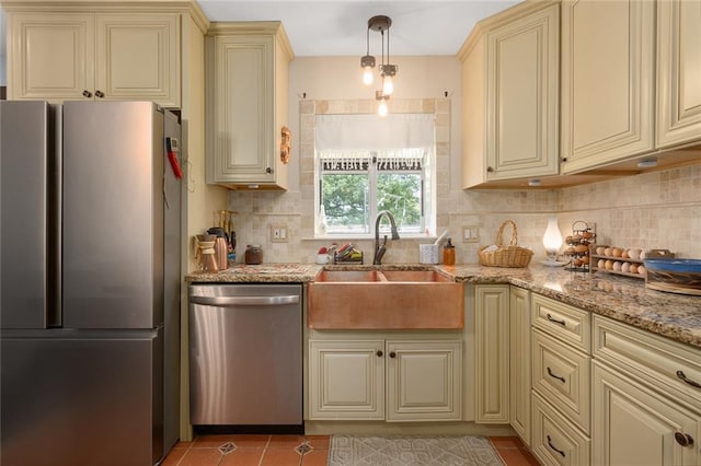 kitchen featuring hanging light fixtures, stainless steel appliances, cream cabinets, and sink